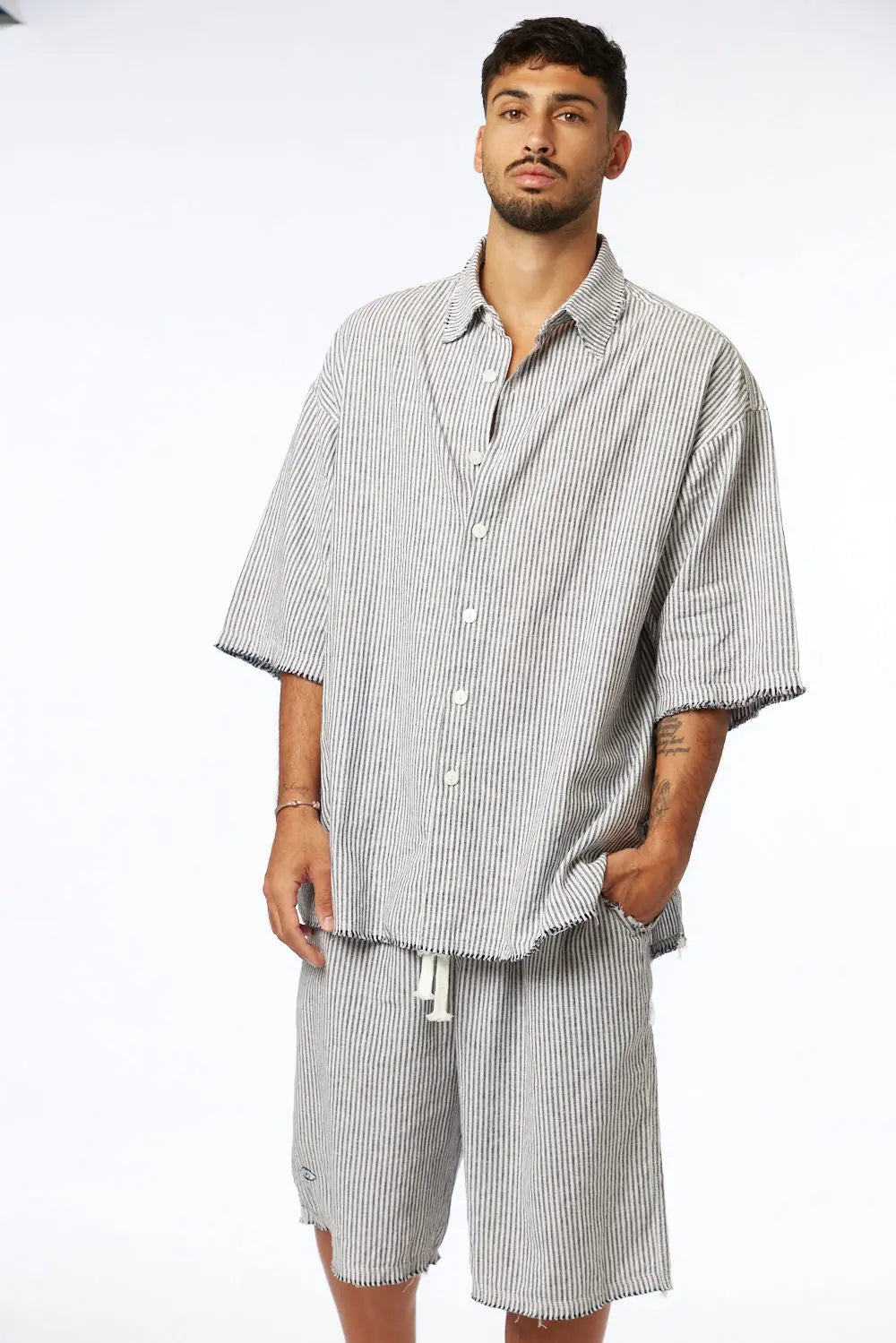 Man wearing black striped Bermuda shorts and matching short-sleeved shirt