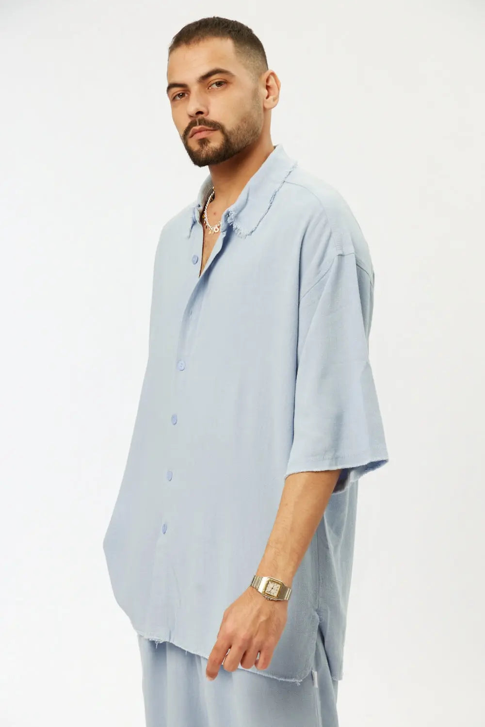 Man wearing a light blue shirt and pants on a white background