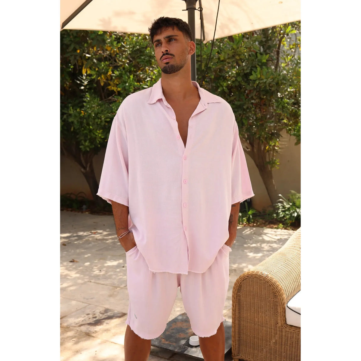 Man wearing a Soft Linen Short Sleeve Button-Up Shirt in Baby Pink with matching shorts