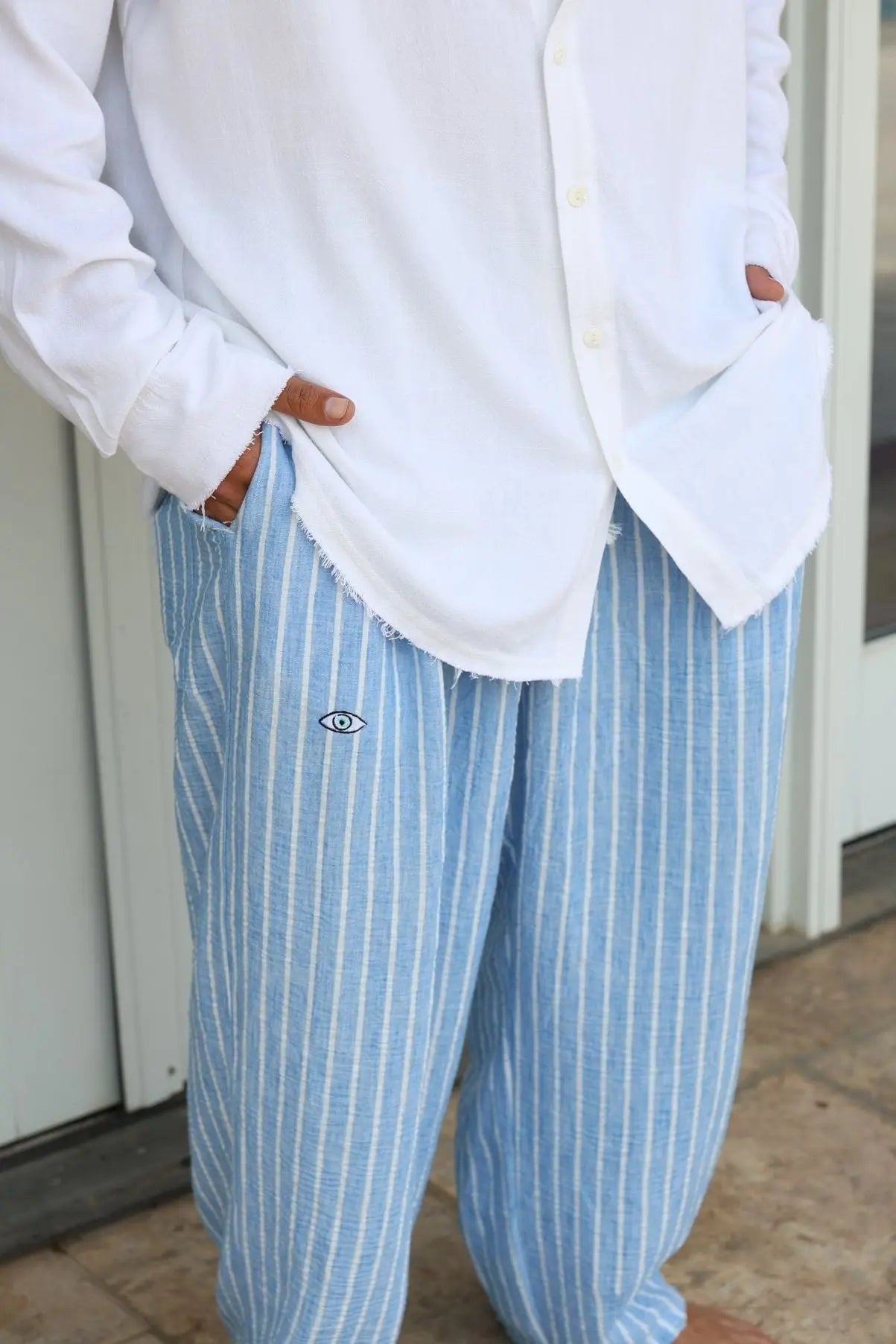 Pure Oversized Linen Pants in Sky Blue Stripes with an eye logo, worn with a white shirt