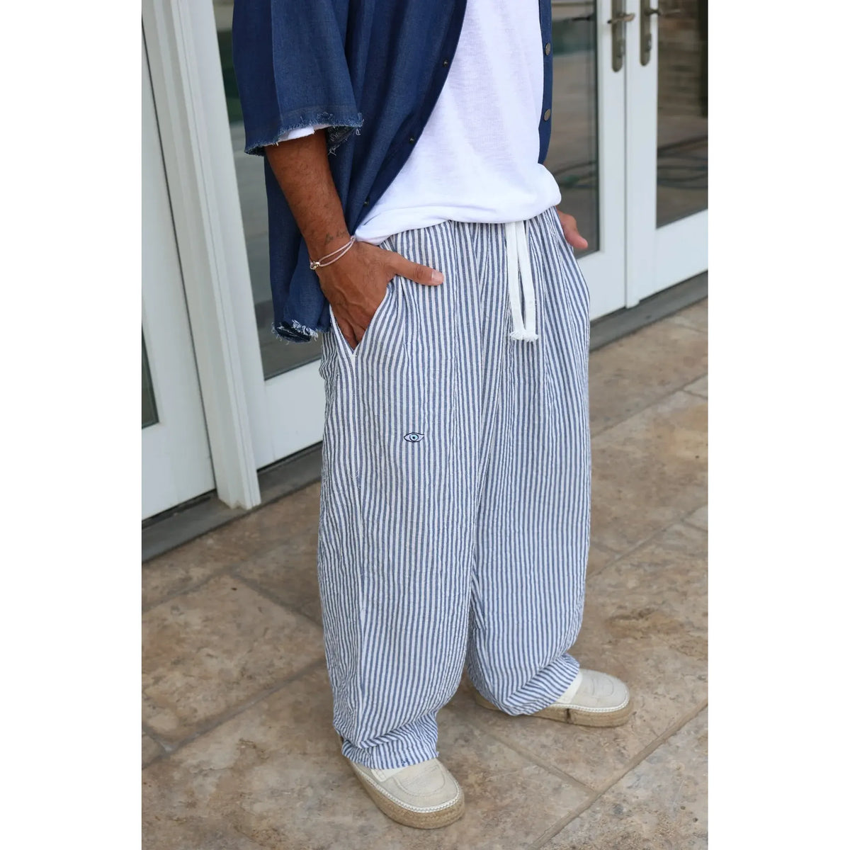 Pure Oversized Linen Pants in blue and white stripes, worn with a white t-shirt, blue denim shirt, and espadrilles