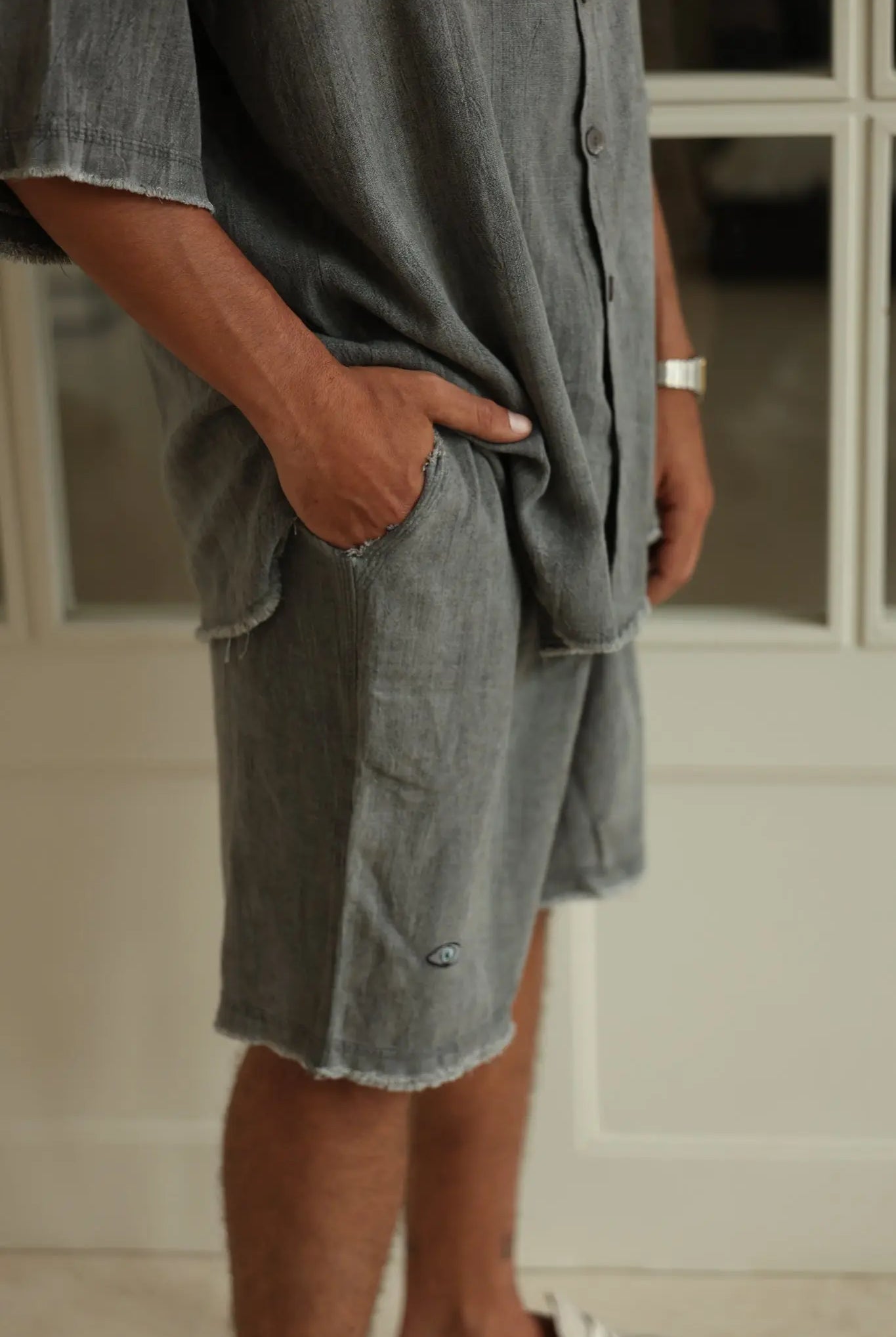 Person wearing a gray oversized shirt and shorts with a blurred background