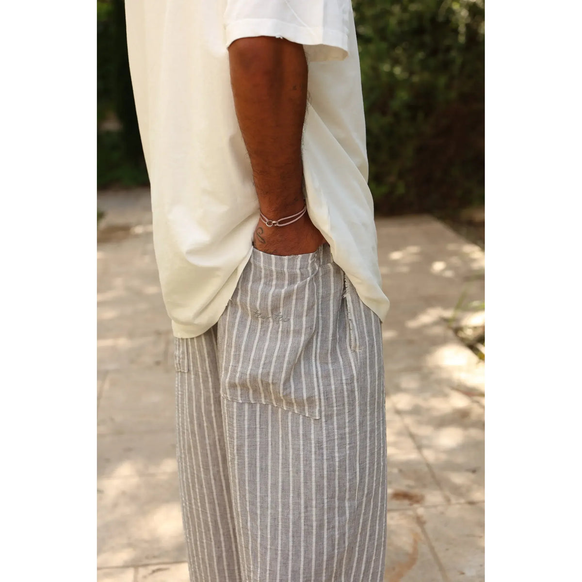Pure Oversized Linen Pants in grey and white stripes, with a person's hand in the pocket