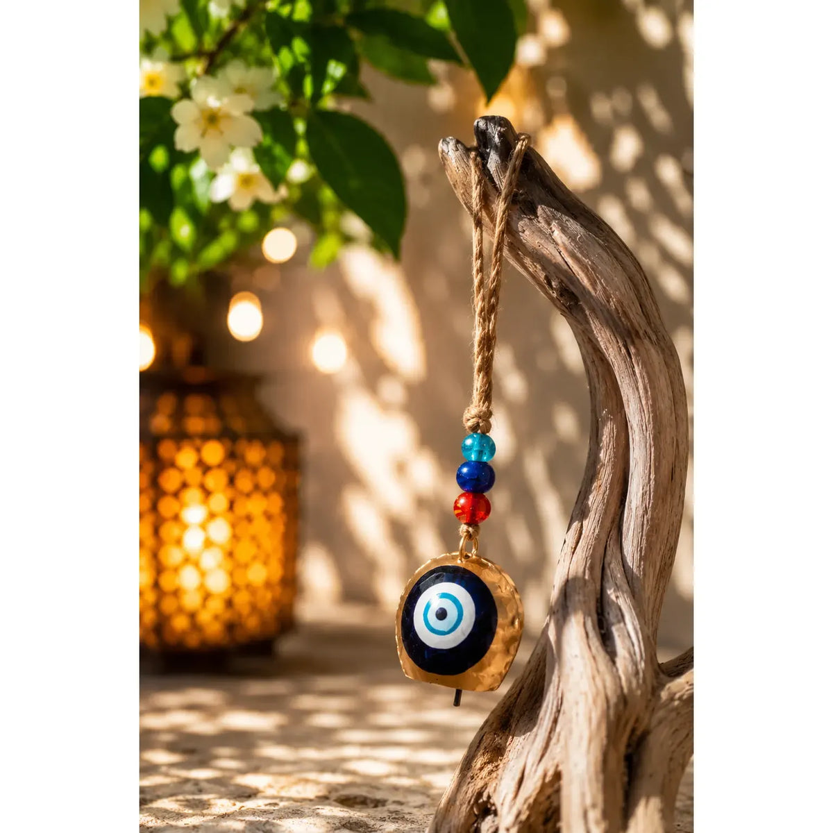 Single Hanging Bell Mobile with an evil eye charm and colorful beads, hanging from a piece of driftwood