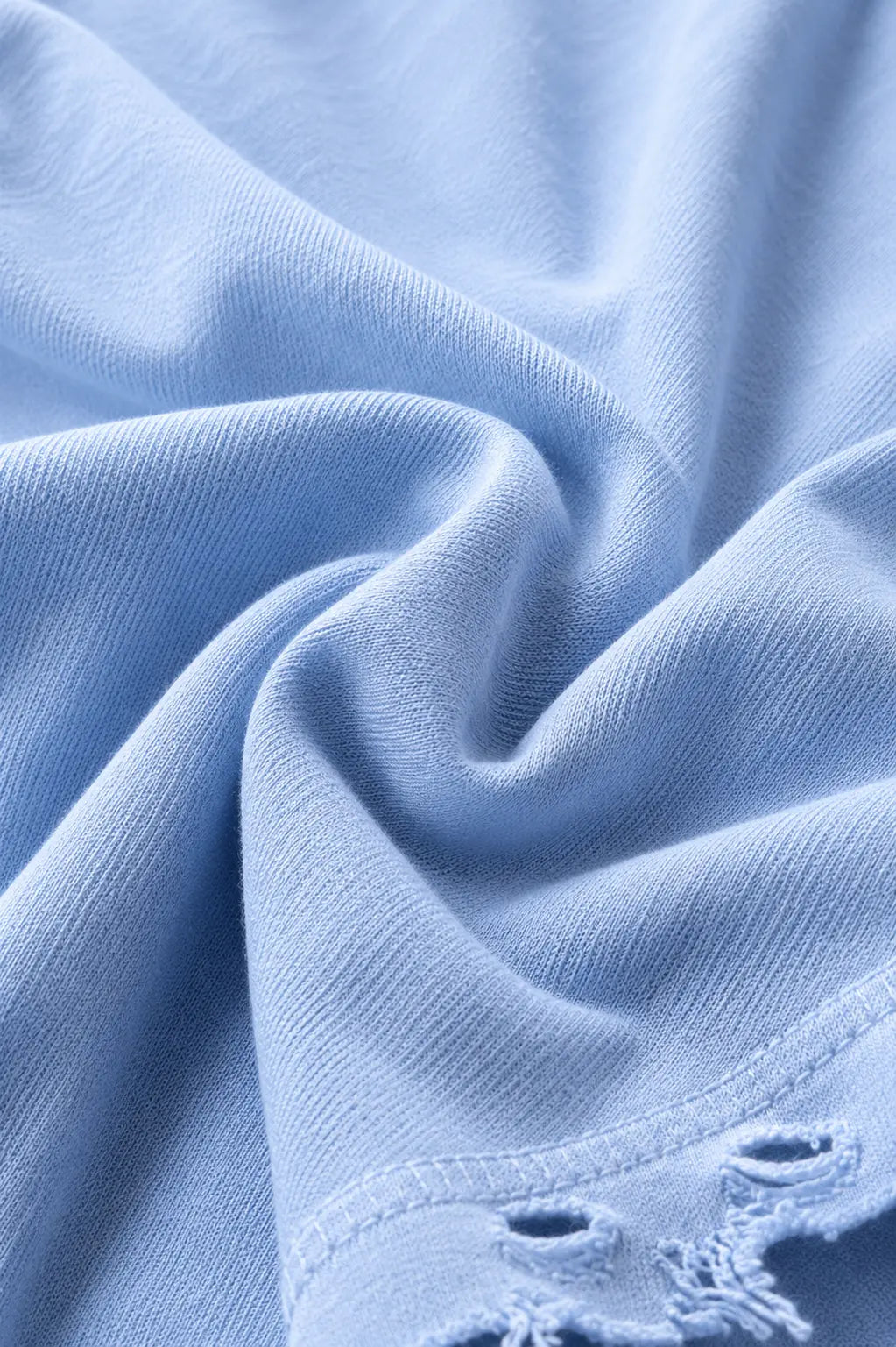Close up of light blue Dor Oversized Shirt fabric with visible texture and distressed hem