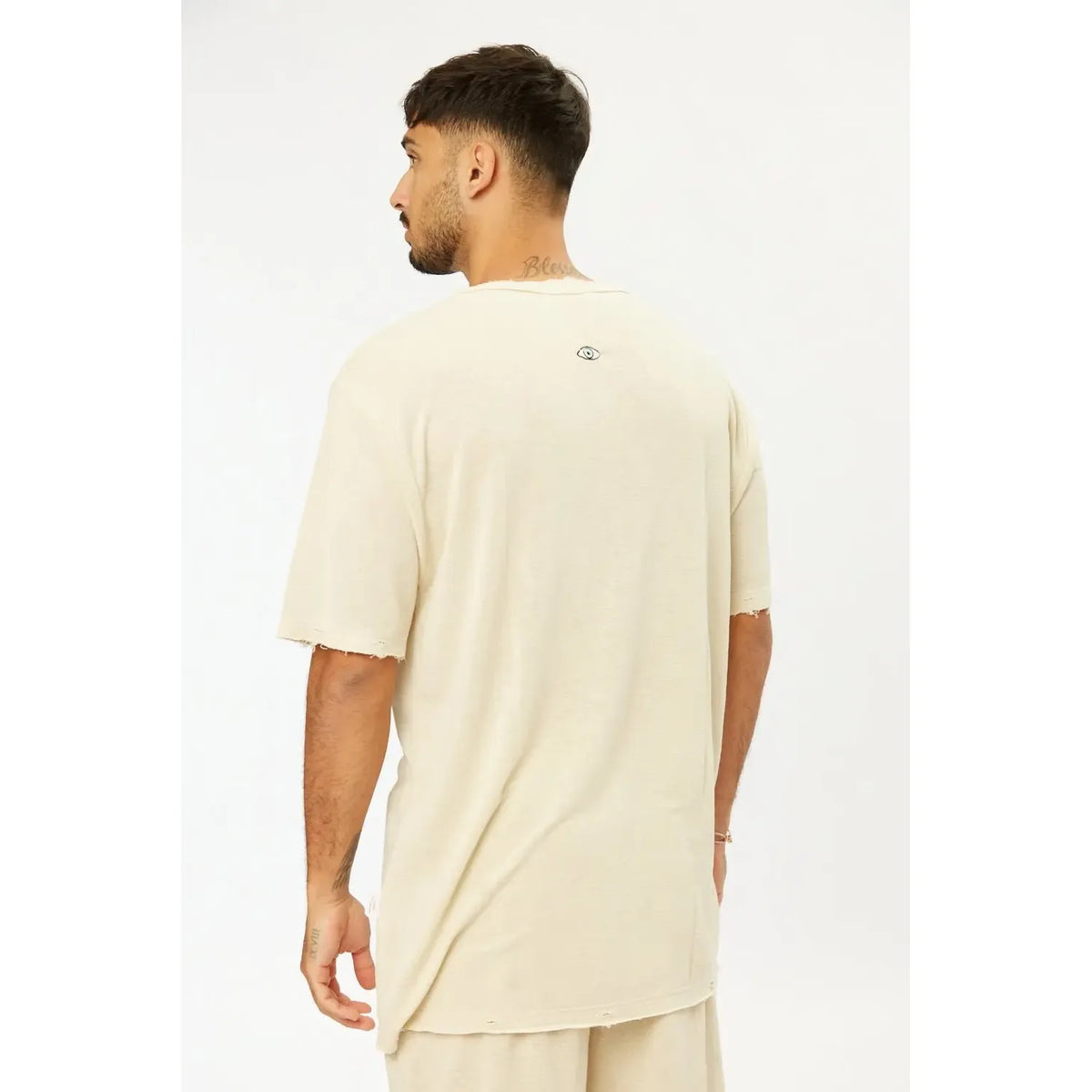 Man from behind wearing a TFU Soft Essential Tee in light stone with a small eye graphic on the back