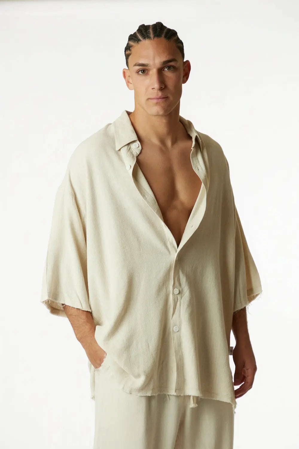 Soft Linen Short Sleeve Button-Up Shirt in Melange Stone, worn by a man with braided hair, standing with one hand in his pocket