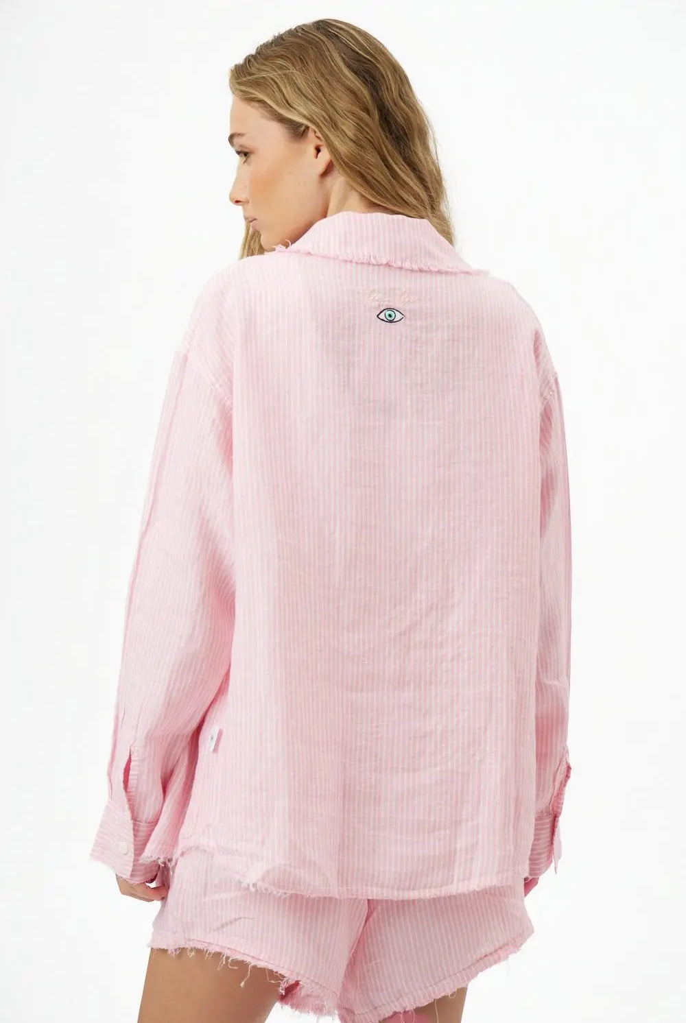 Back of a woman wearing a Pure Linen Women's Button-Up Shirt in pink and white stripes with an eye graphic on the back