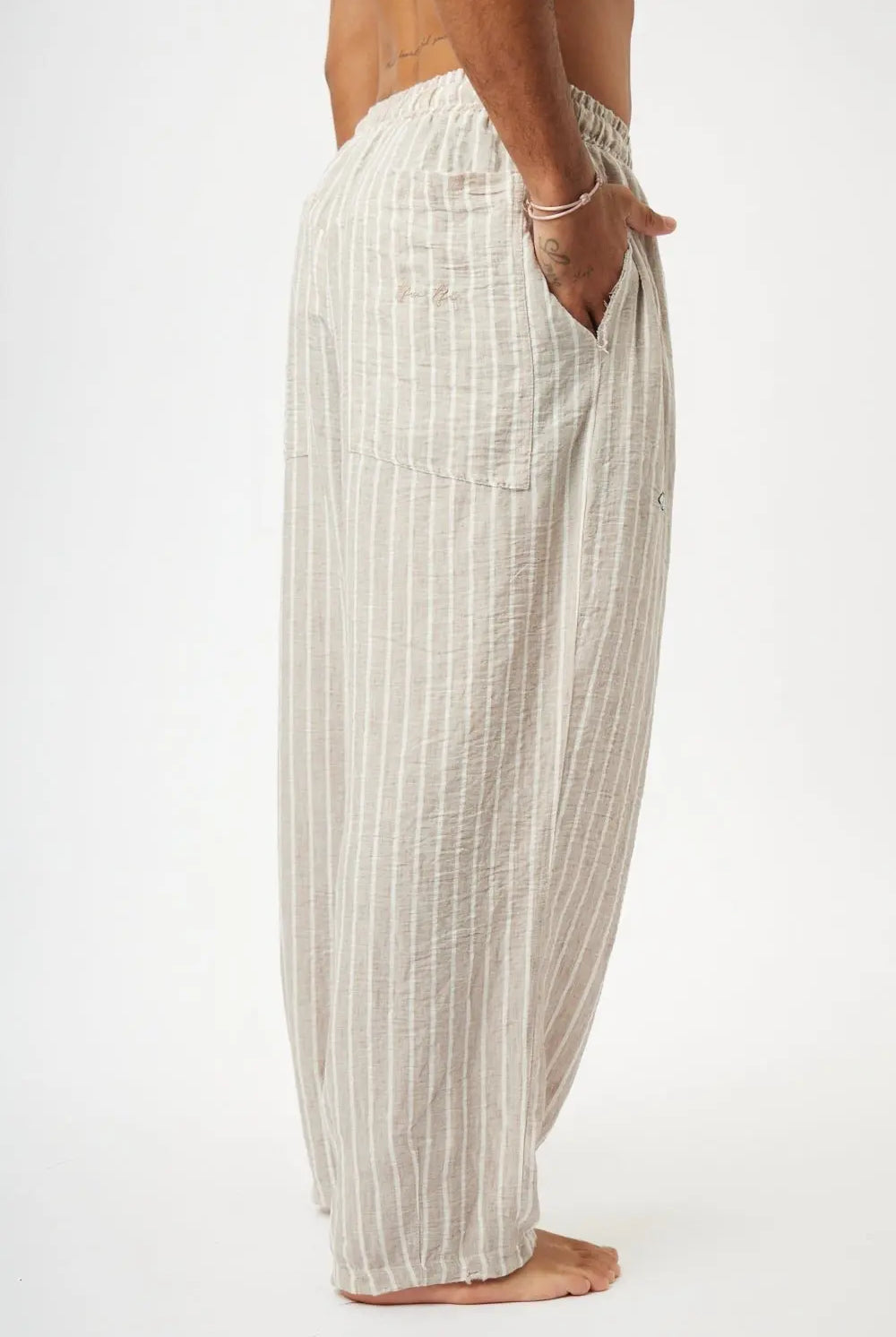 Pure Oversized Linen Pants in Stone & White Stripes, side view, with a hand in the pocket