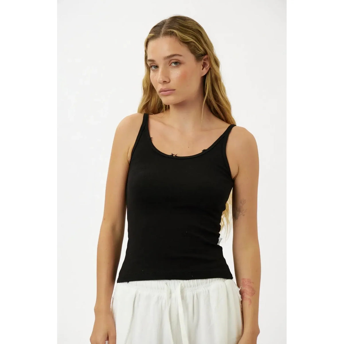 Slim Cotton Tank Top in black worn by a woman with long blonde hair and white pants