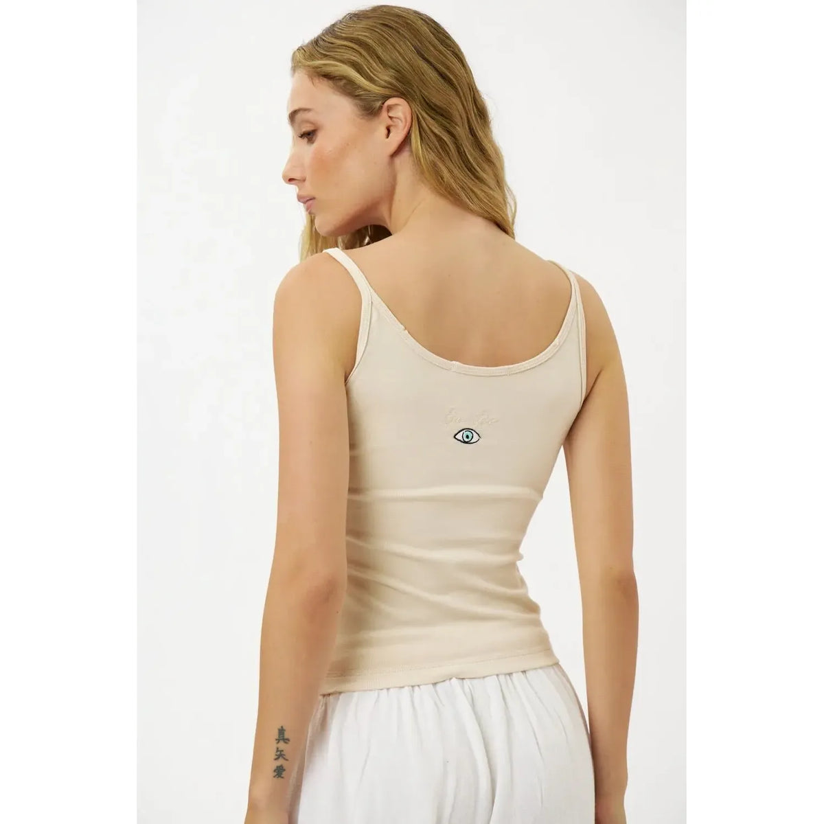 Back of a woman wearing a Slim Cotton Tank Top in Stone with an embroidered eye graphic