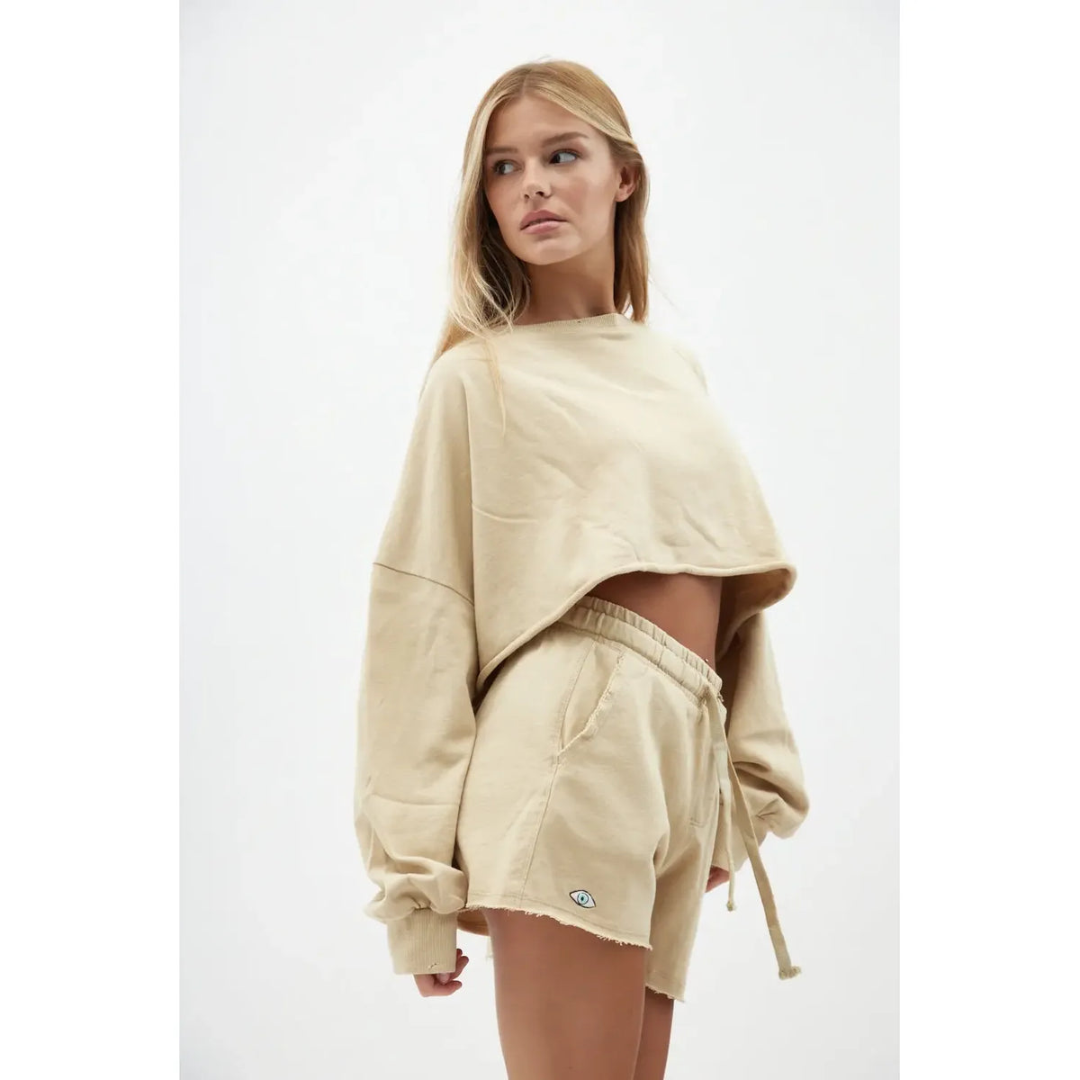 Woman wearing a beige sweatshirt and shorts set on a white background