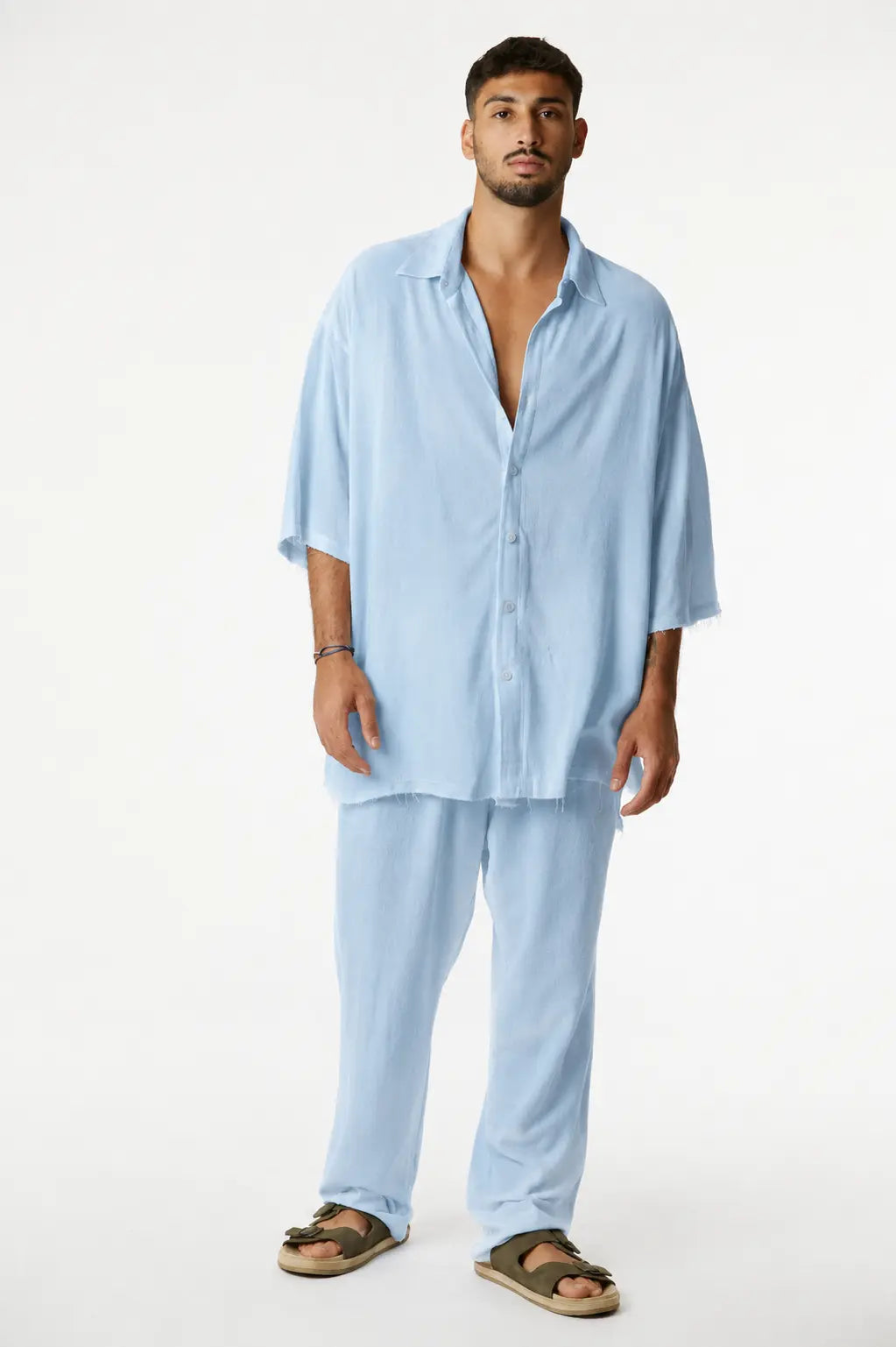 Man wearing a Soft Linen Short Sleeve Button-Up Shirt in Ice Blue with matching pants and sandals