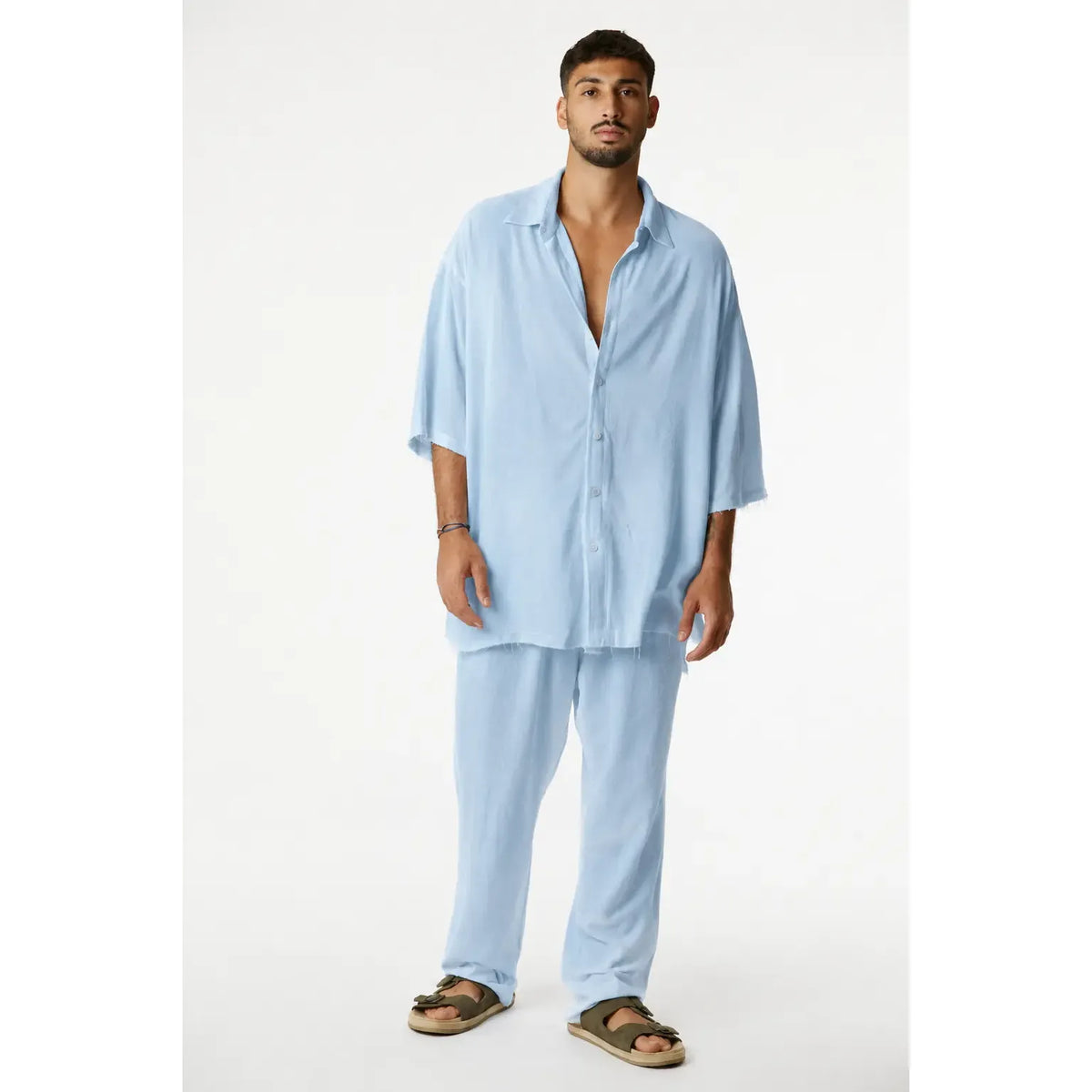 Man wearing a Soft Linen Short Sleeve Button-Up Shirt in Ice Blue with matching pants and sandals