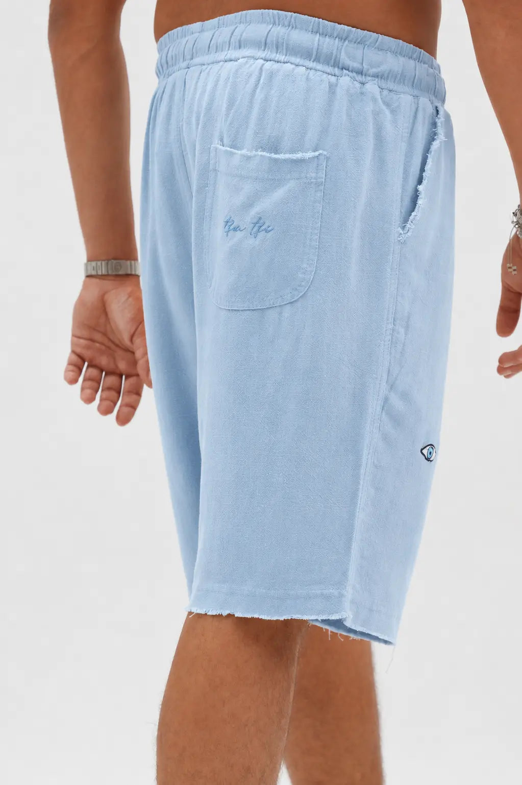Soft Linen Bermuda Shorts in Sky Blue, with a back pocket and a small eye logo on the side