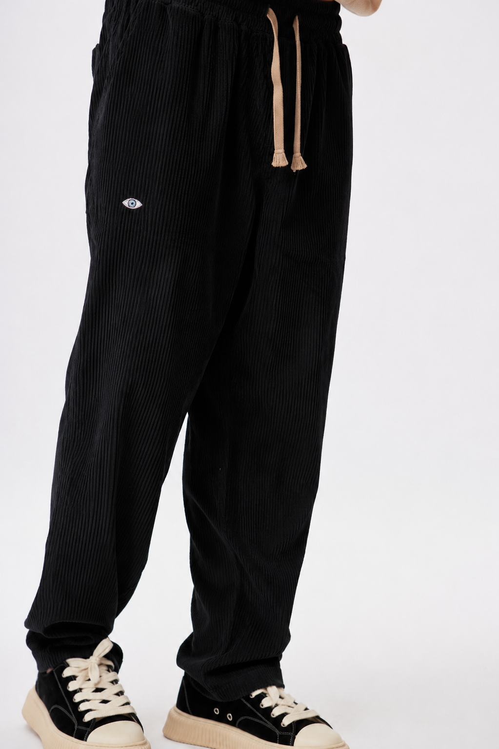 Black corduroy pants with a small logo on a white background