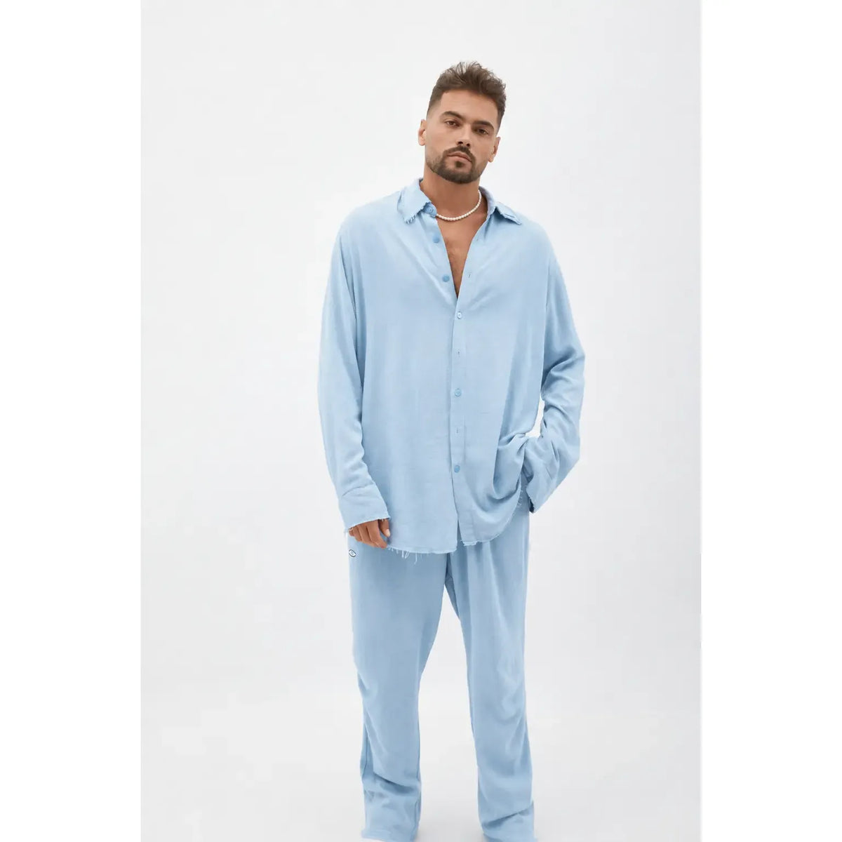 Man wearing a Soft Linen Long Sleeve Button-Up Shirt in Ice Blue with matching pants and a pearl necklace