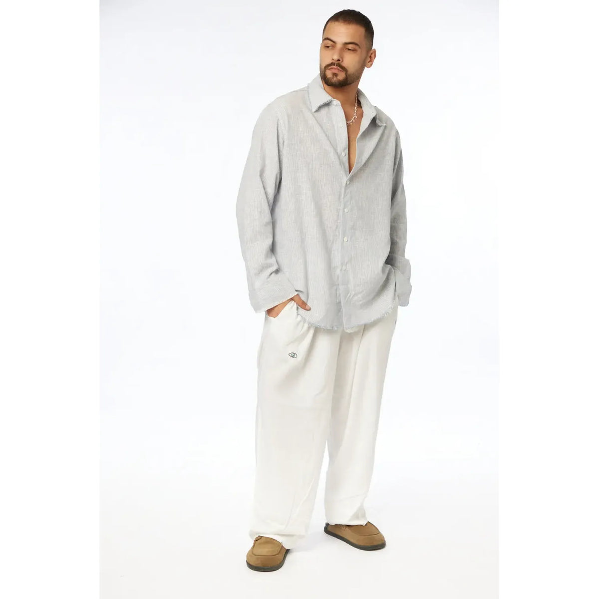 Man wearing a blue striped PURE long sleeve linen button-up shirt and white pants