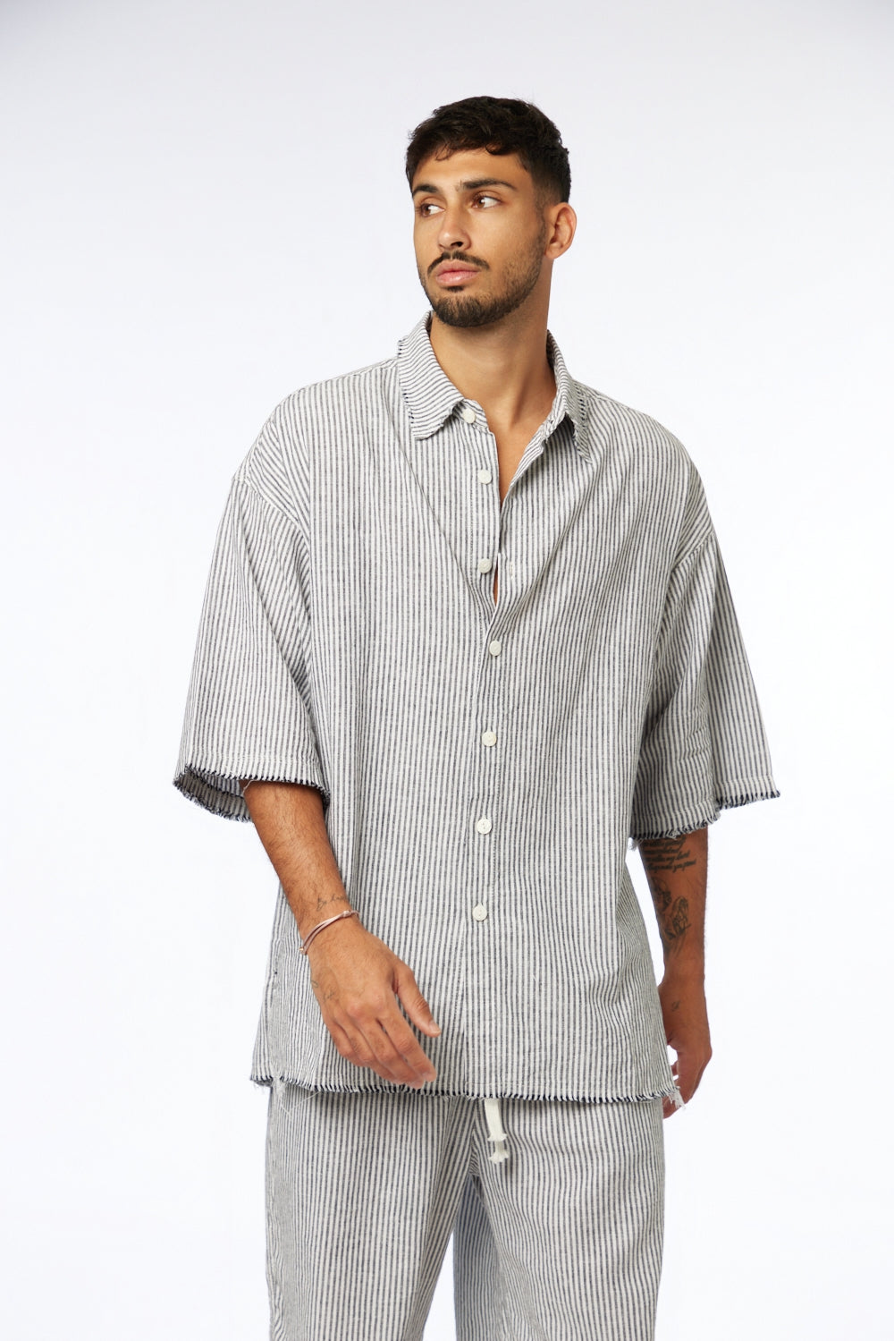 Man wearing a black striped linen short sleeve button-up shirt and matching pants