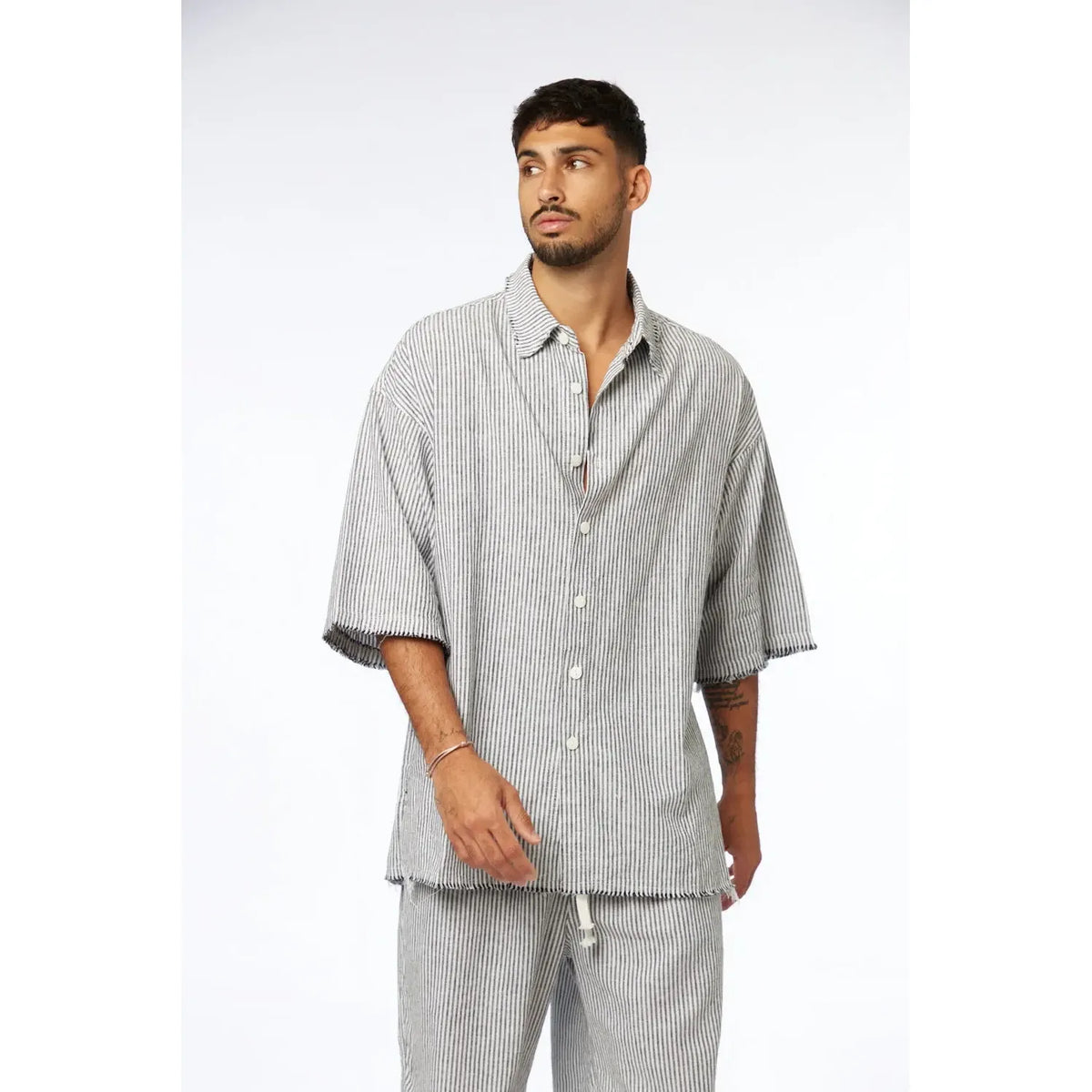 Man wearing a black striped linen short sleeve button-up shirt and matching pants