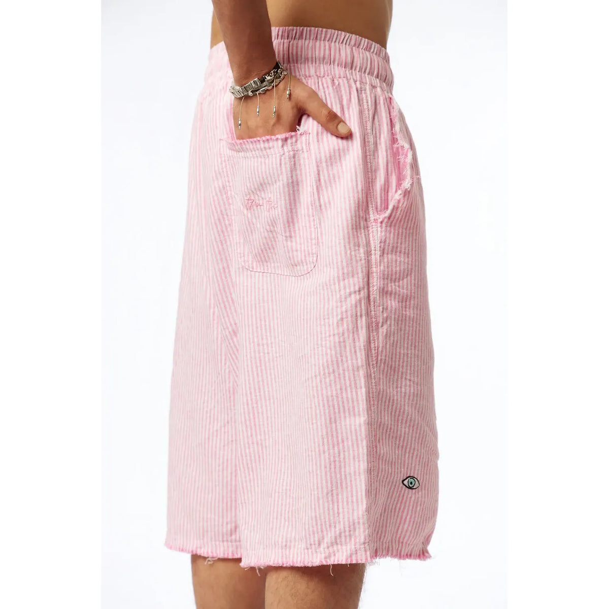 Striped Bermuda Shorts in pink with white stripes, a hand in the pocket, and an eye graphic on the lower leg
