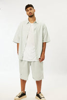 Man wearing a white oversized shirt and shorts on a white background