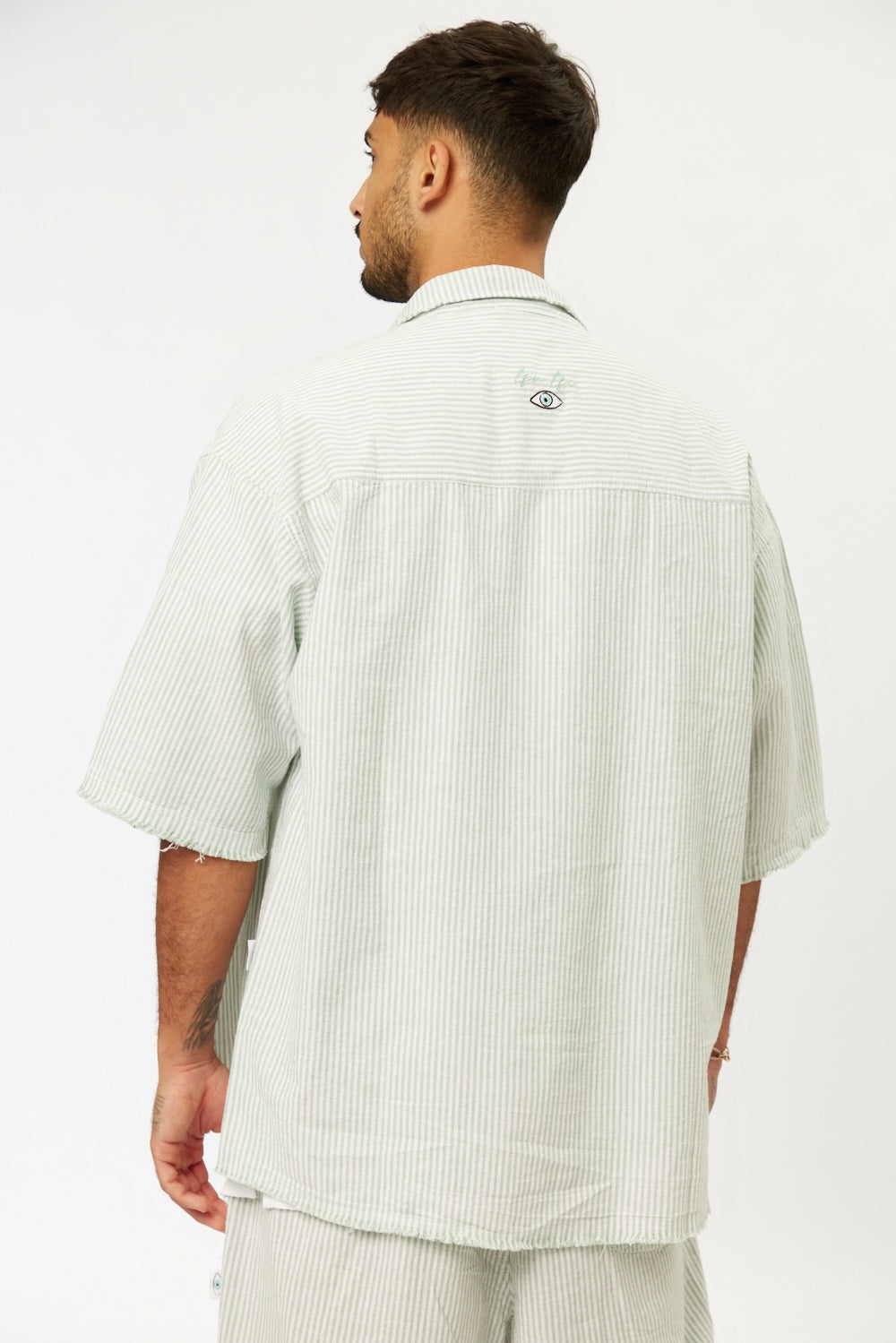 Man from behind wearing a green striped linen short sleeve button-up shirt