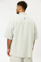 Man from behind wearing a green striped linen short sleeve button-up shirt