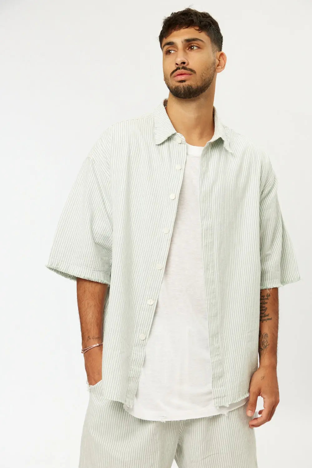 Man wearing a green striped linen short sleeve button-up shirt over a white t-shirt and matching striped shorts