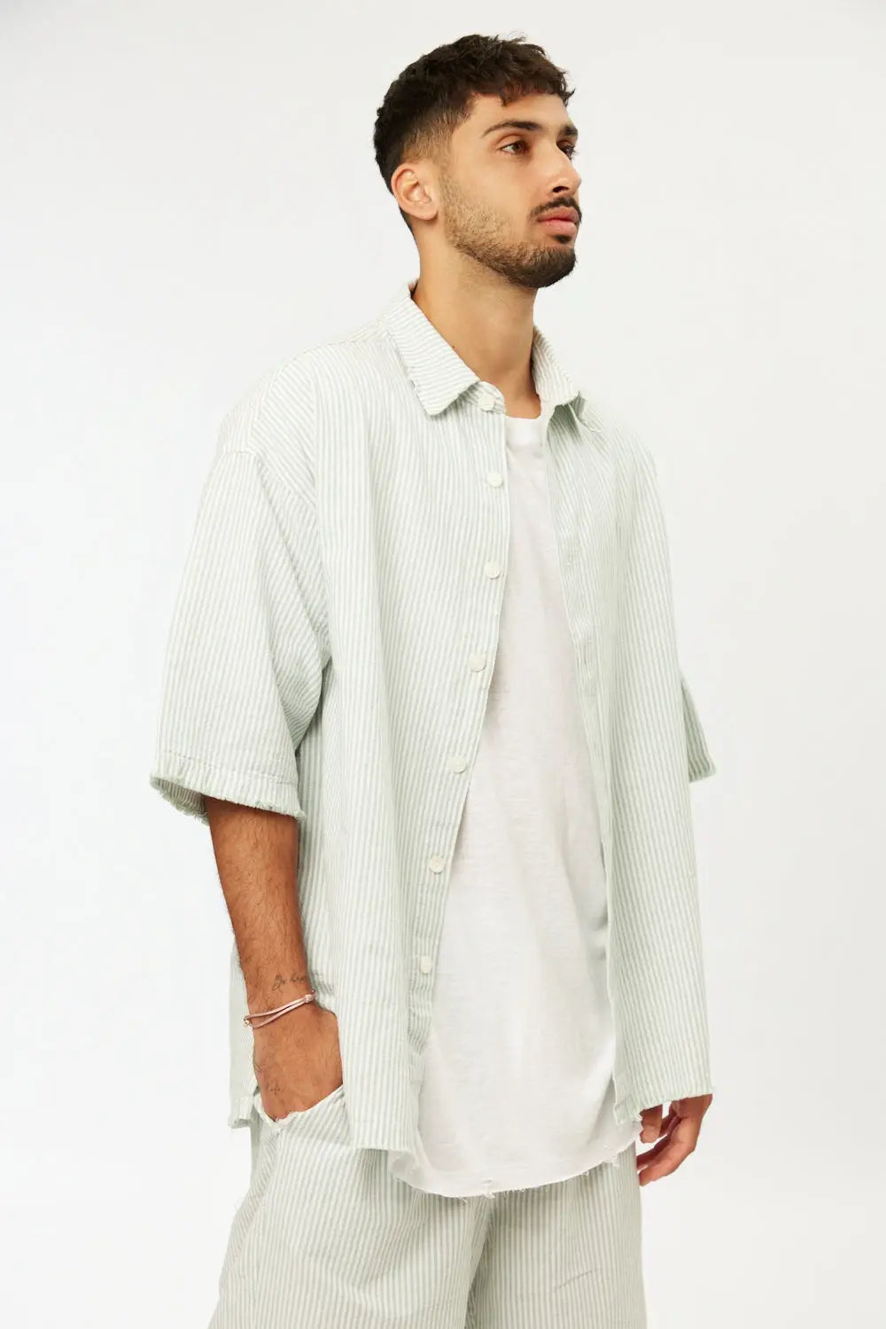 Man wearing a green striped linen short sleeve button-up shirt over a white t-shirt and matching striped shorts
