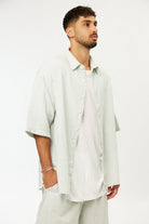Man wearing a green striped linen short sleeve button-up shirt over a white t-shirt and matching striped shorts