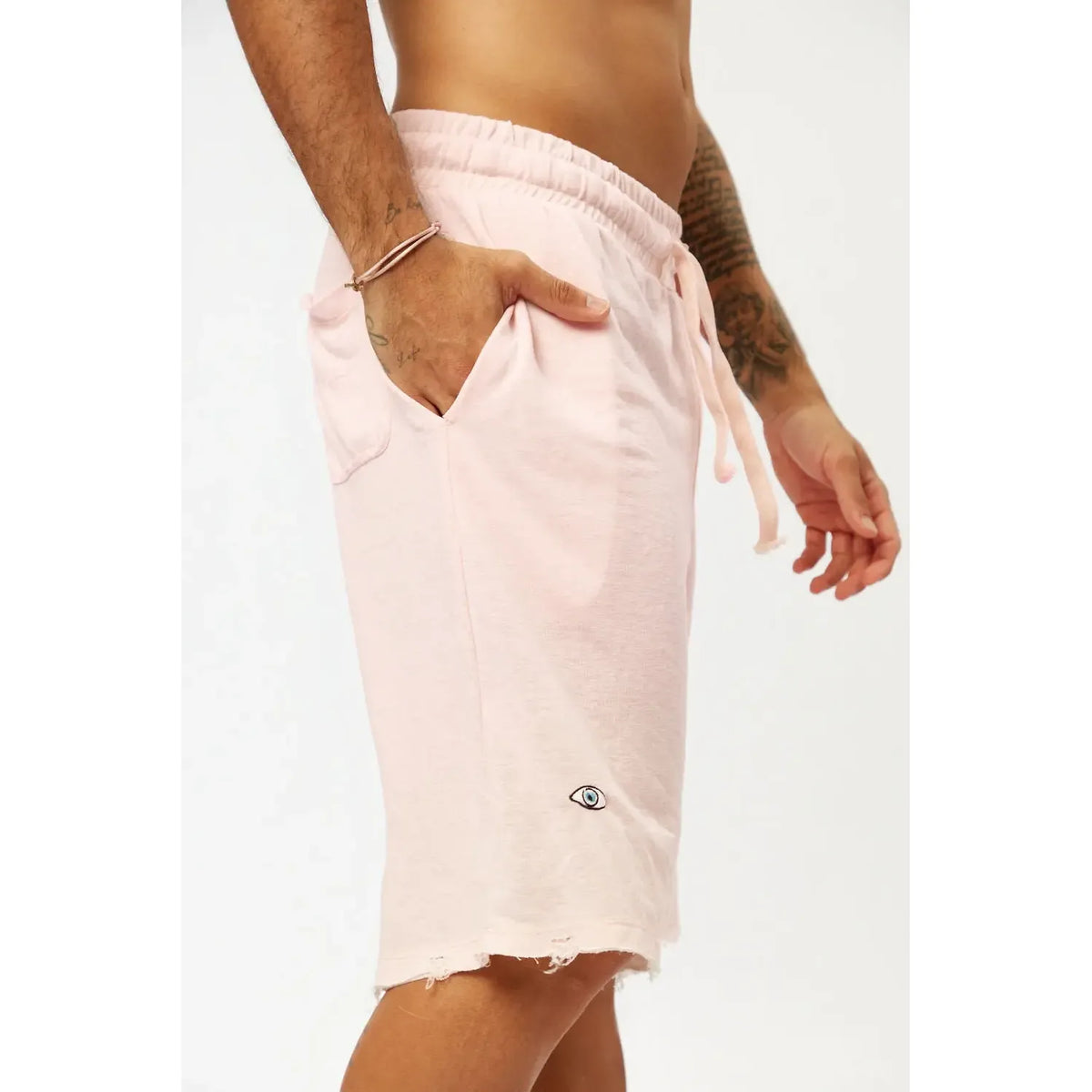 Base Shorts in baby pink with a drawstring waist and an eye logo on the left leg