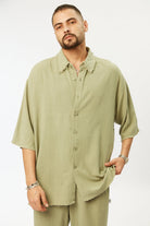 Man wearing a light green shirt and pants on a white background
