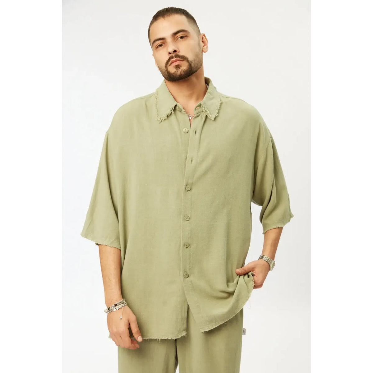 Man wearing a light green shirt and pants on a white background