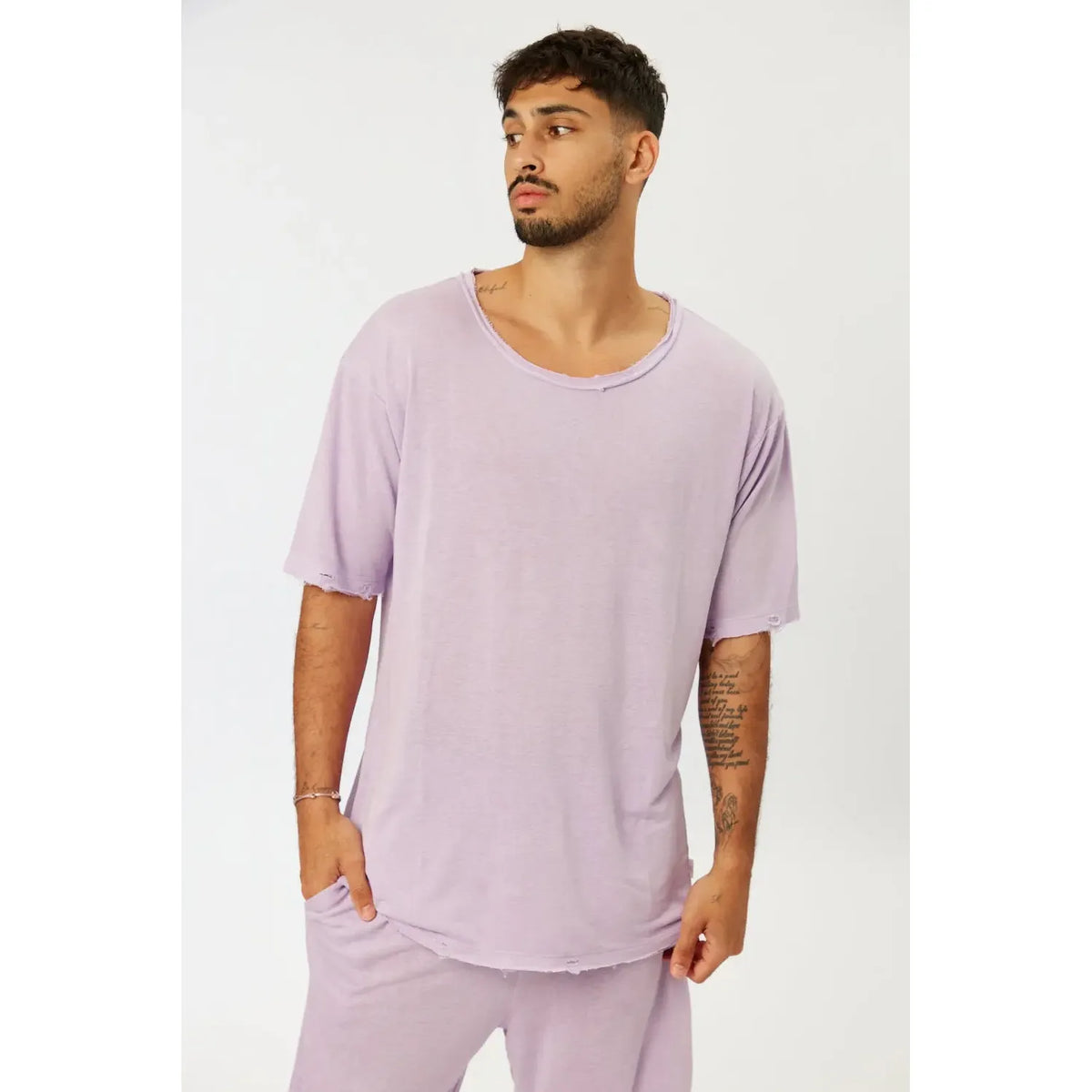 Man wearing a Nicki Soft Open Top in purple, with distressed edges on the collar and sleeves