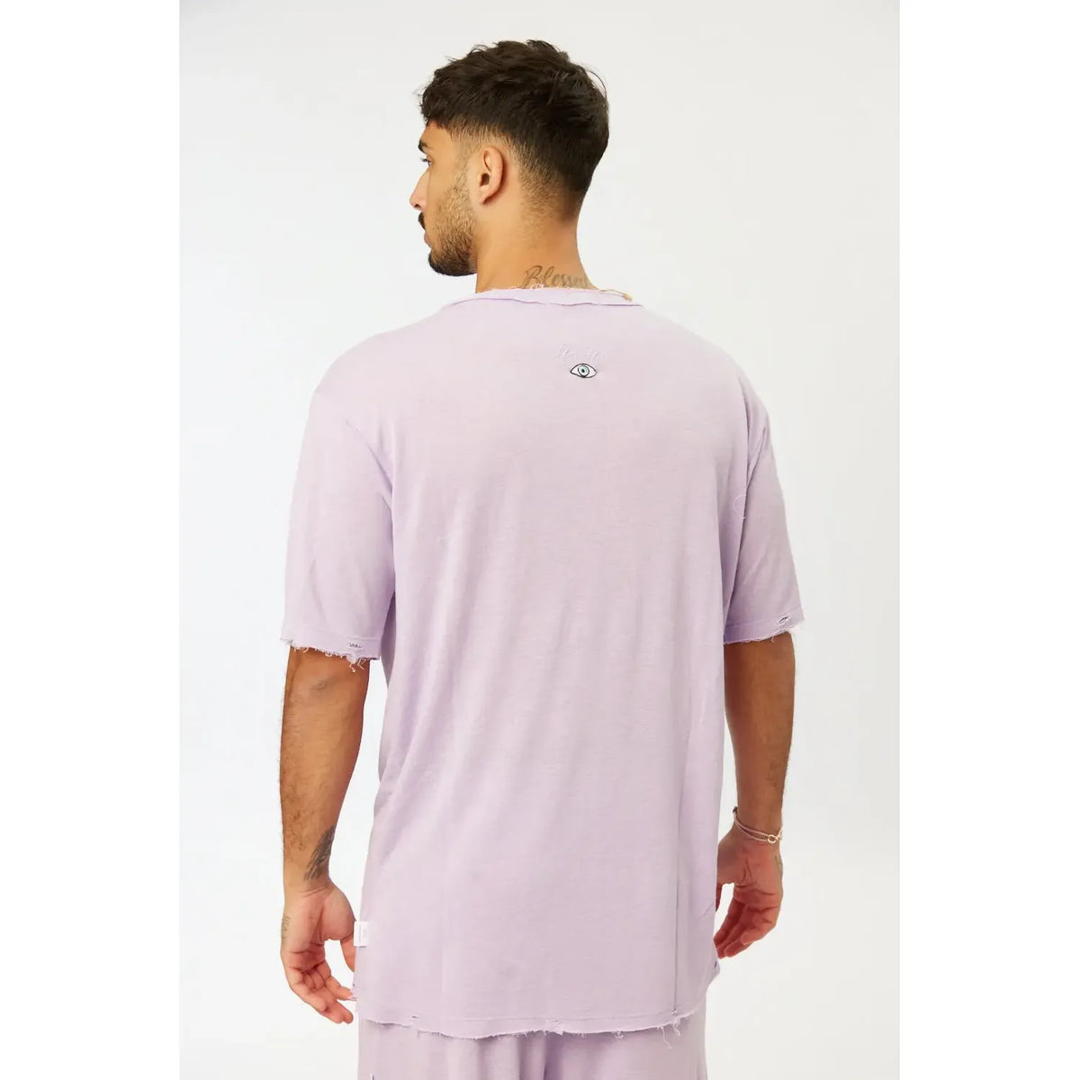 Back of a man wearing a purple Nicki Soft Open Top with a small eye graphic on the upper back