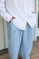 Pure Oversized Linen Pants in Sky Blue Stripes with an eye logo, worn with a white shirt