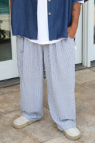 Pure Oversized Linen Pants in blue and white stripes, worn with a white t-shirt and blue denim shirt