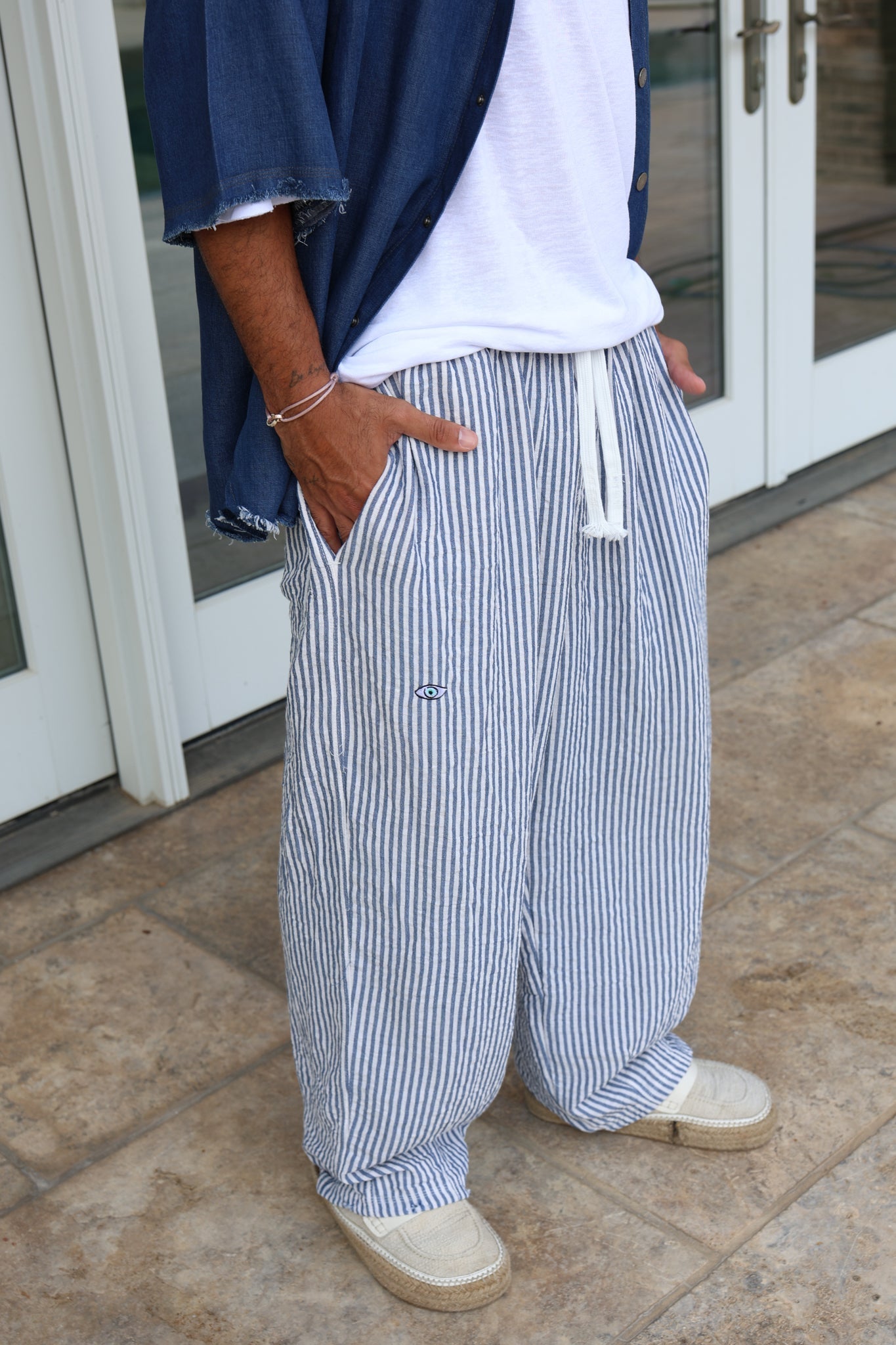 Pure Oversized Linen Pants in blue and white stripes, worn with a white t-shirt, blue denim shirt, and espadrilles