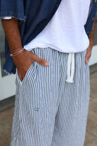 Pure Oversized Linen Pants in blue and white stripes with a white drawstring and an evil eye emblem