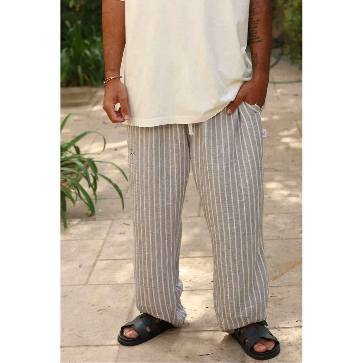Pure Oversized Linen Pants in grey and white stripes, worn with a white t-shirt and black sandals
