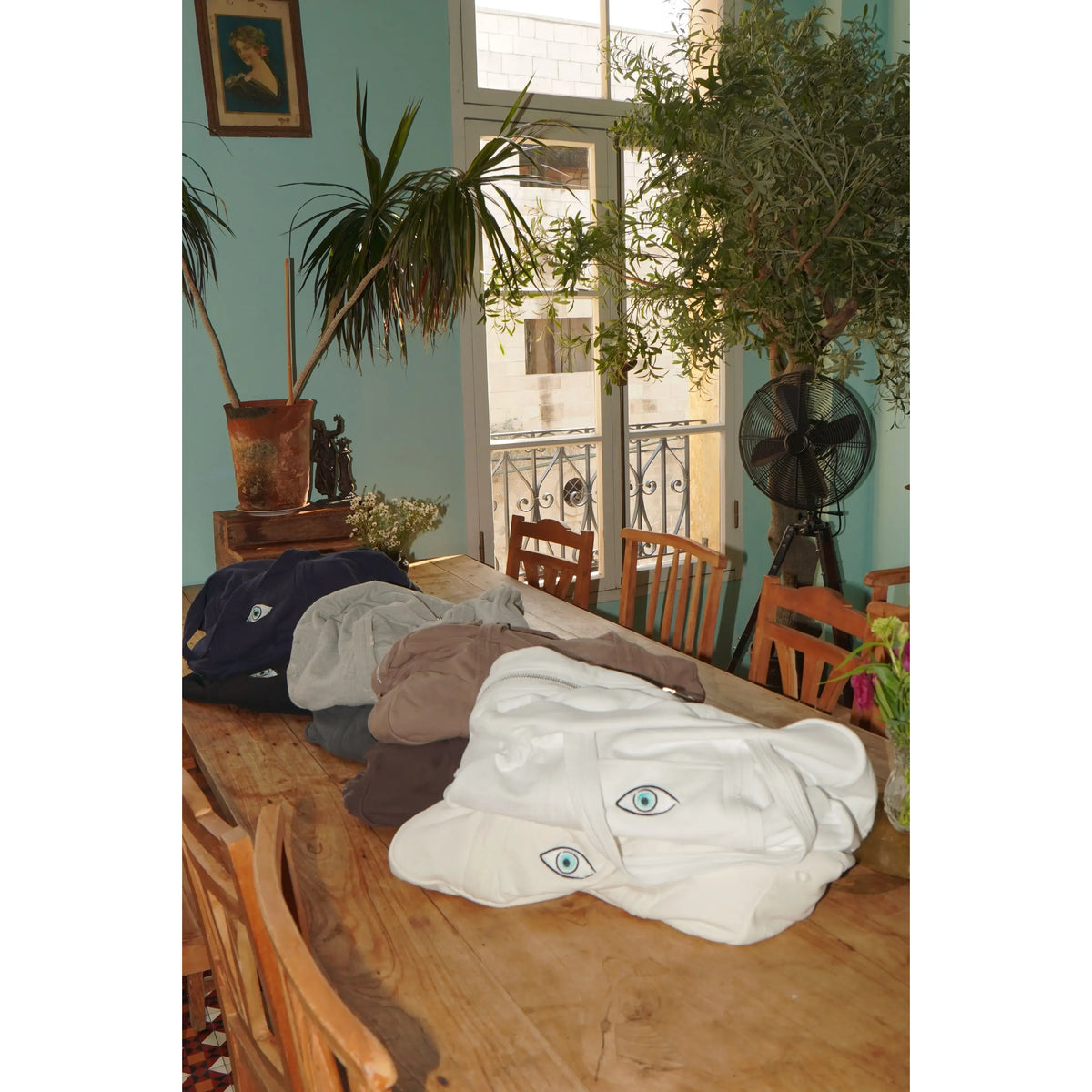 Cotton Bag - White, with an eye design, on a wooden table with other bags