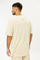 Man from behind wearing a TFU Soft Essential Tee in light stone with a small eye graphic on the back