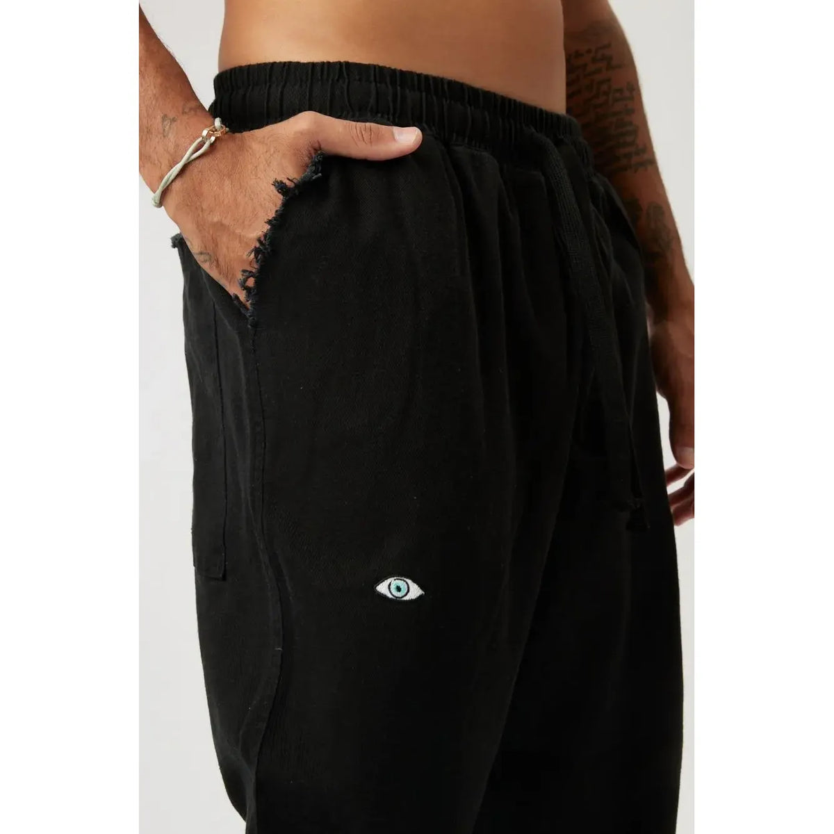 Close up of DC Elastic Waist Pants with Elastic Hem in black, showing the ripped pocket and eye graphic