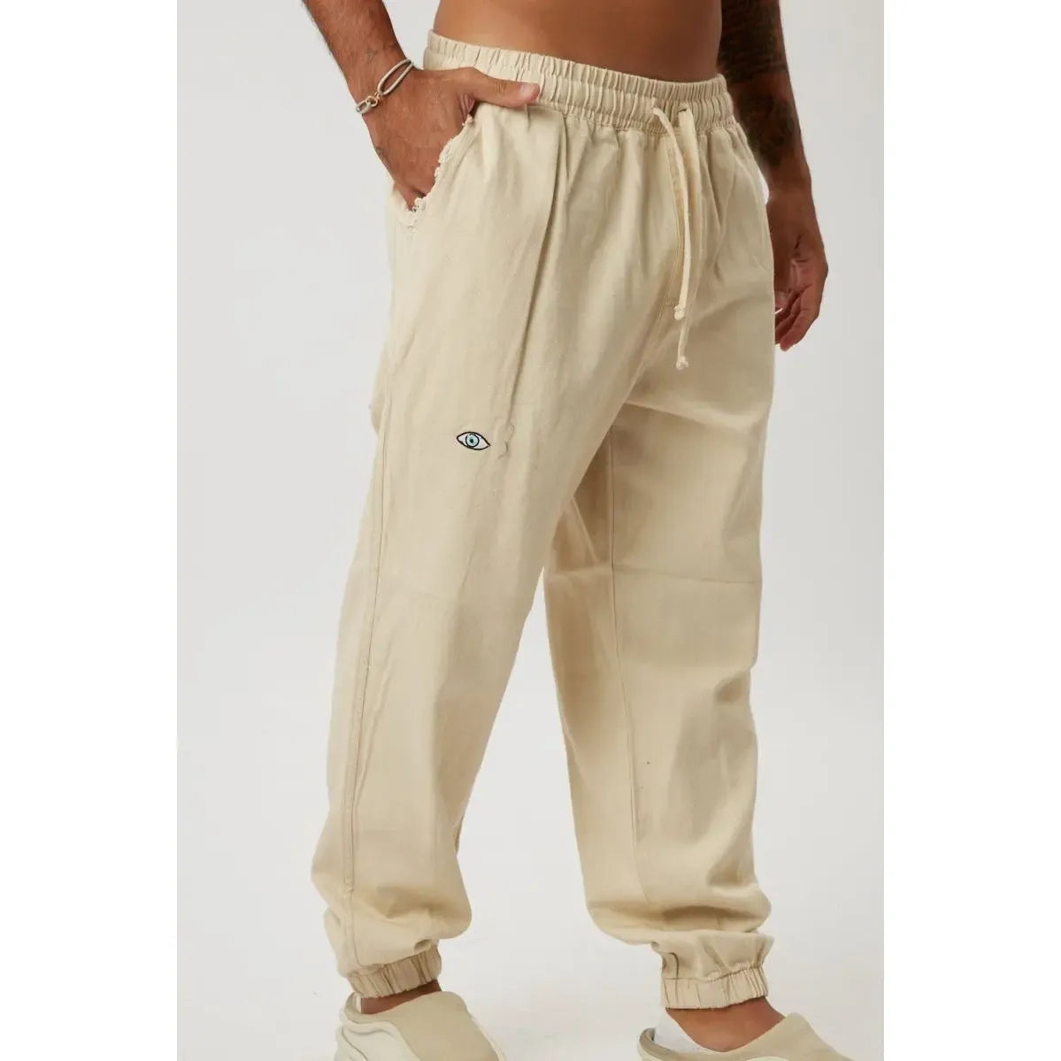 Stone DC Elastic Waist Pants with Elastic Hem, featuring an eye logo on the left thigh and a drawstring waist