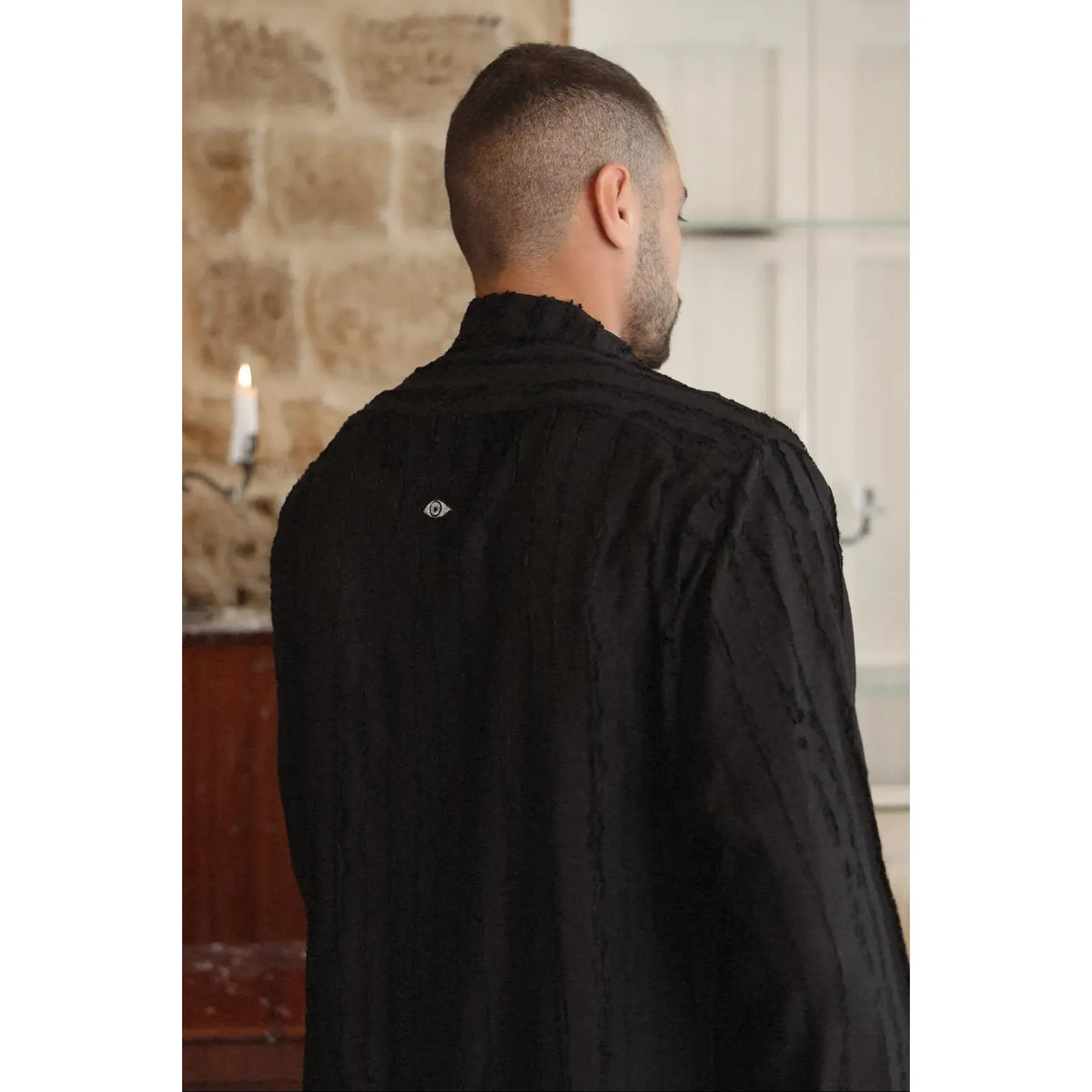 Man from behind wearing a black RIPS Long Sleeve Button-Up Shirt with an eye logo on the back