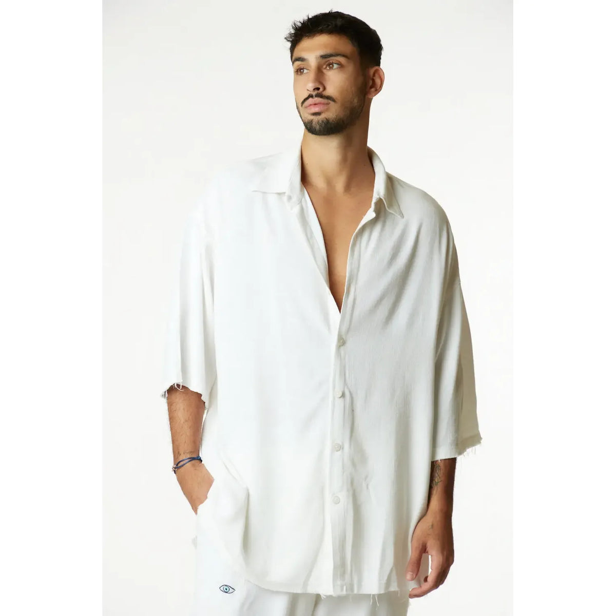 Man wearing a white oversized shirt against a plain background
