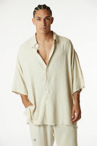 Man wearing a beige shirt and pants on a white background