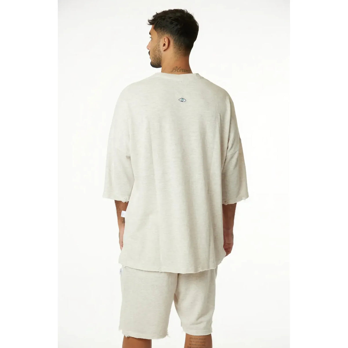 Man from behind wearing a 3/4 Sleeve Nicki Soft in Melange Stone with a small eye graphic on the back