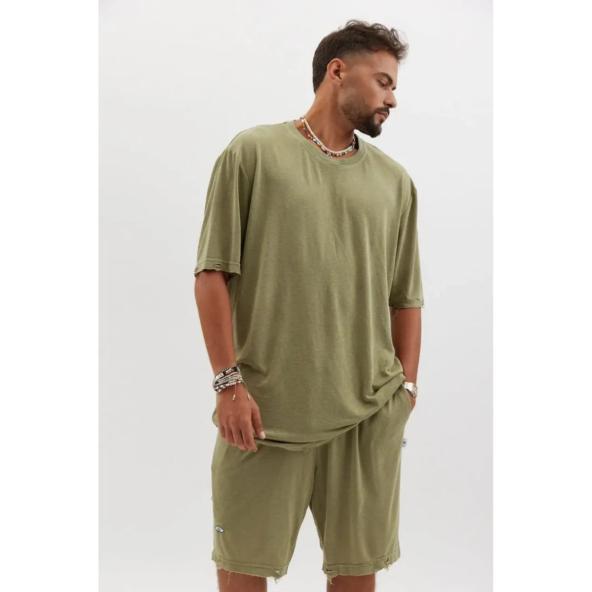 Man wearing TFU Soft Essential Tee in olive with matching shorts, beaded necklaces, and bracelets